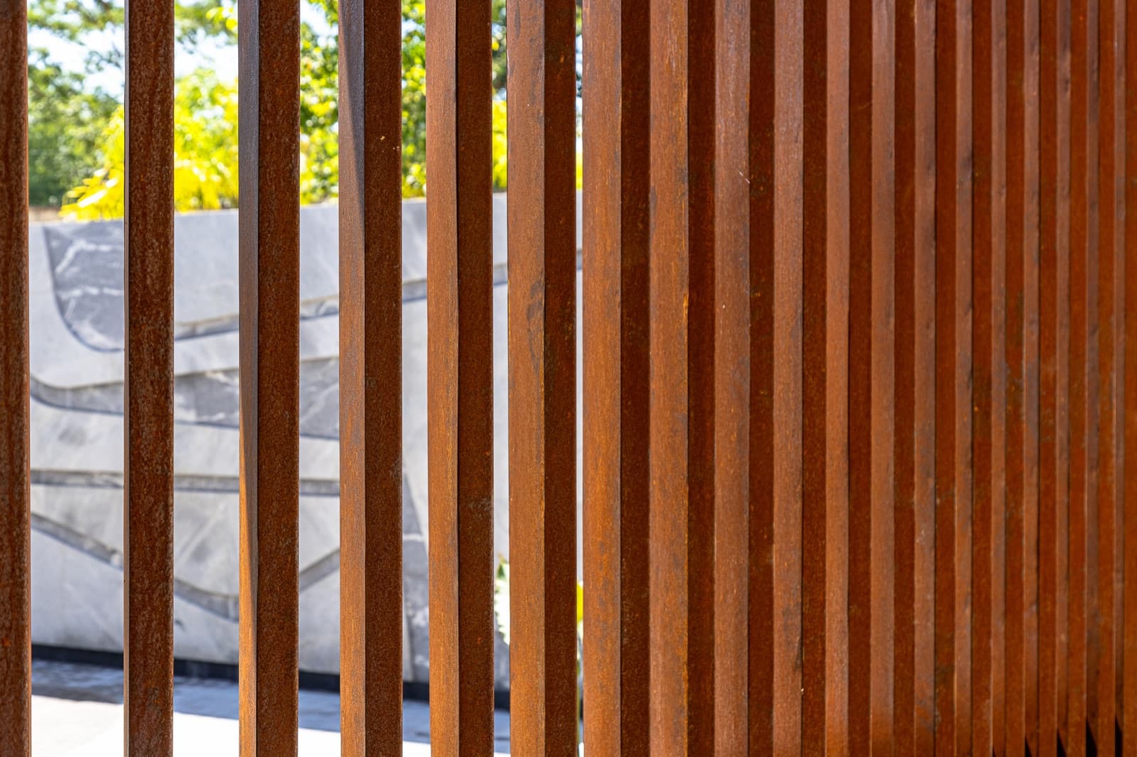 Macro da pátina de aço corten nas ripas verticais, com a textura avermelhada em primeiro plano